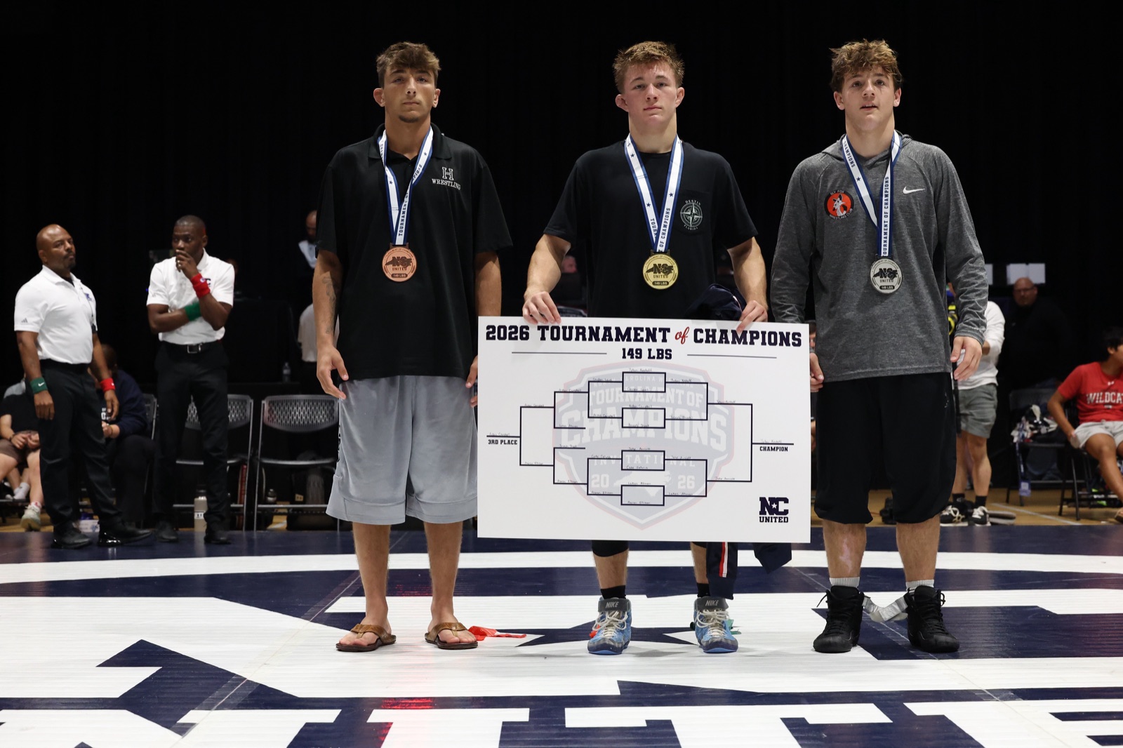 The 149 lb podium at the 2026 Tournament of Champions — the three placers on the mat, the champion holding the bracket
