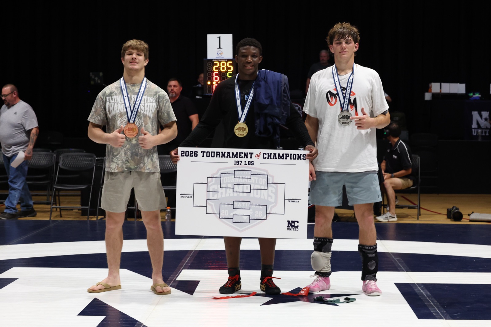 The 197 lb podium at the 2026 Tournament of Champions — the three placers on the mat, the champion holding the bracket